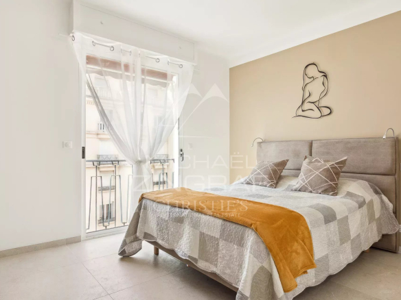 Chambre d'un appartement rénové à Cannes avec un lit double et un balcon.