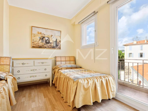 Chambre d'un appartement à Cannes avec deux lits simples et une fenêtre donnant sur l'extérieur.