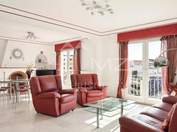 Salon lumineux avec fauteuils en cuir rouge et table en verre, vue sur la mer à Cannes.