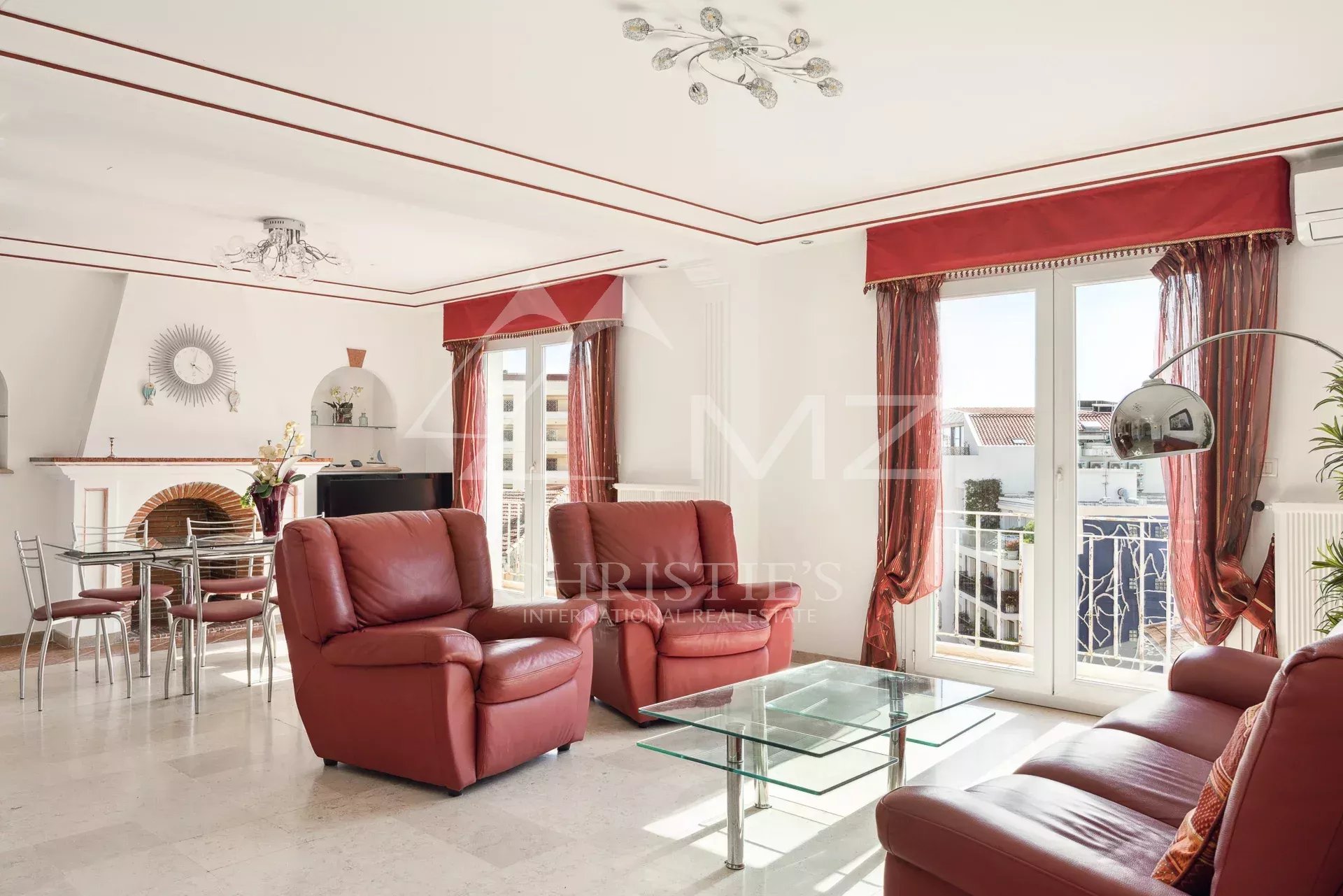 Appartement lumineux à Cannes Salon lumineux avec fauteuils en cuir rouge et table en verre, vue sur la mer à Cannes.