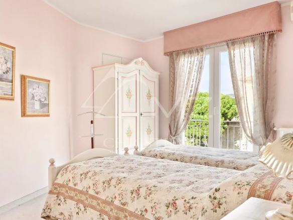 Chambre d'un appartement à Cannes avec lits jumeaux et décoration pastel.