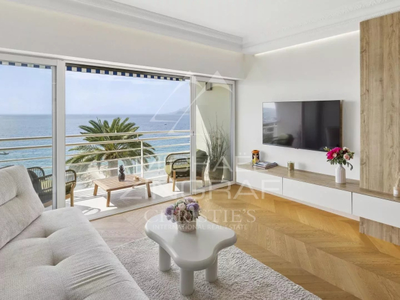 Intérieur d'un appartement moderne avec vue sur la mer, canapé et télévision.