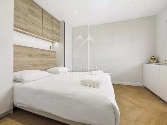 Chambre d'un appartement rénové à Cannes avec lit double et mobilier moderne.
