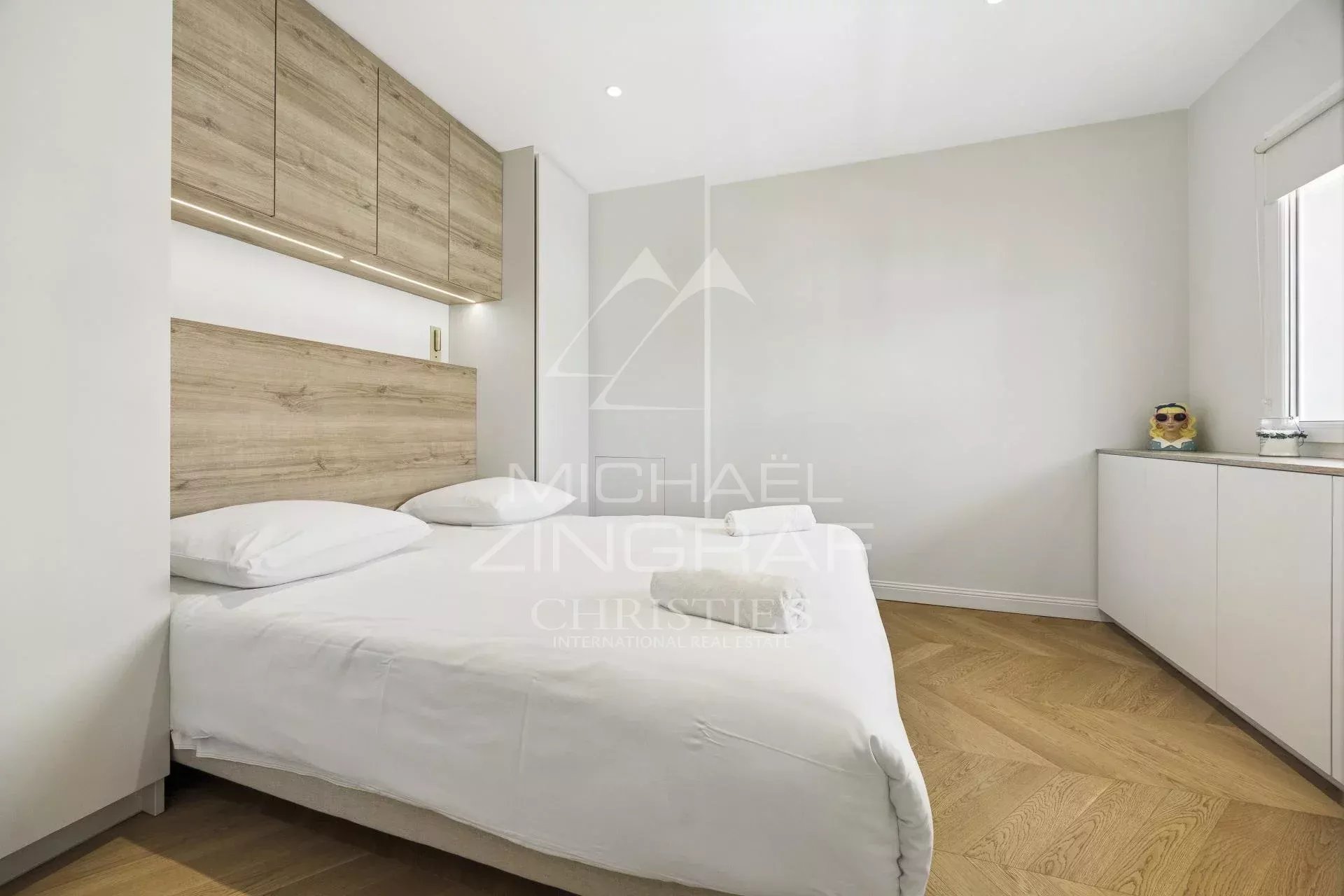 Chambre d'un appartement rénové à Cannes avec lit double et mobilier moderne.