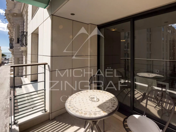 Terrasse d'un appartement 2 pièces à Cannes avec table et chaises, vue sur la rue.