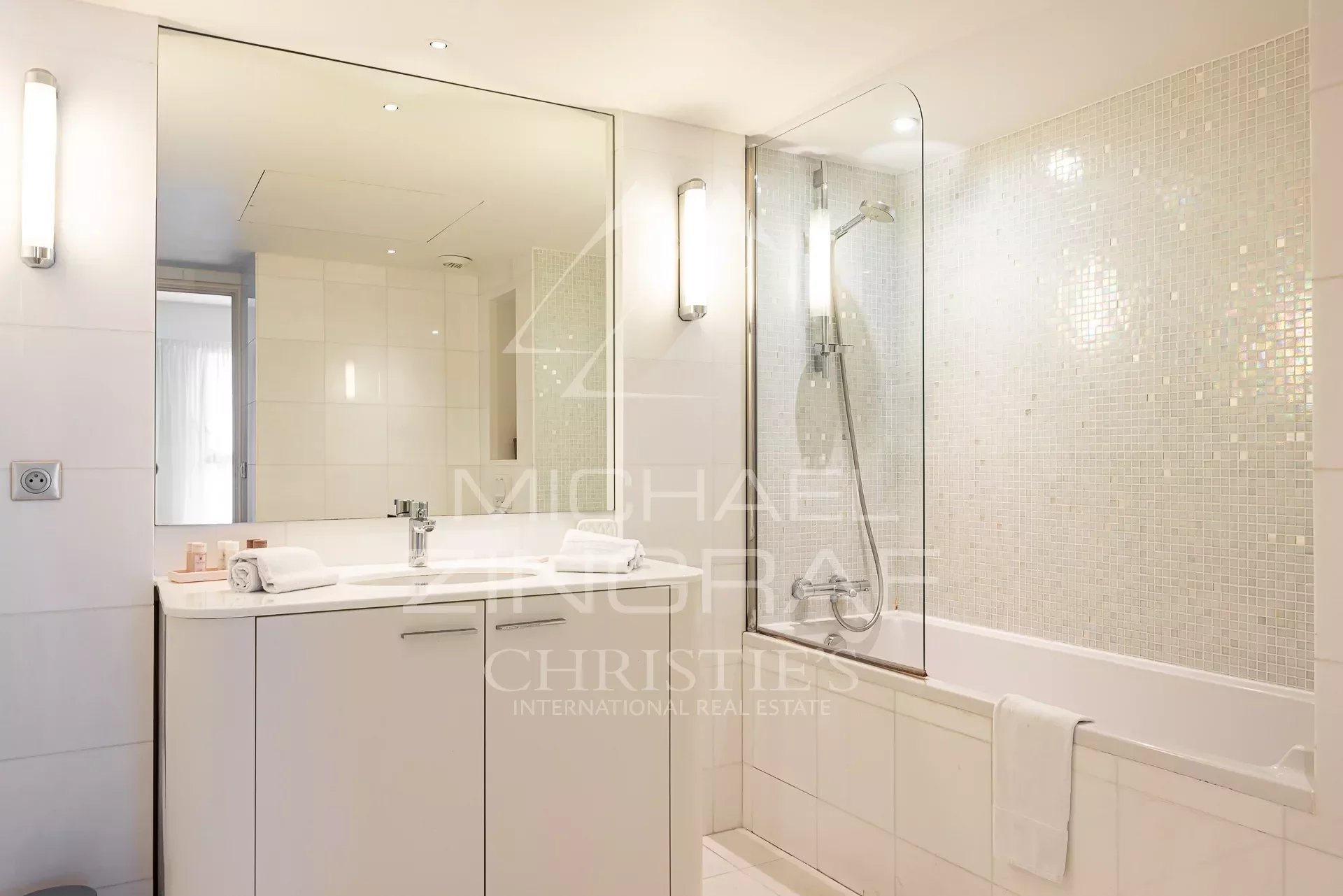 Contemporary bathroom Modern bathroom with bathtub and shower, light tiles and illuminated mirror.