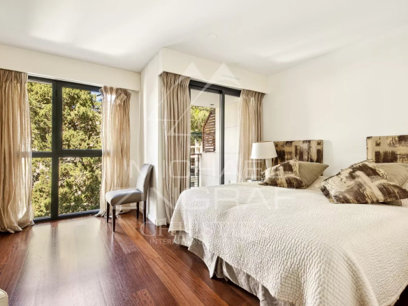 Bedroom in a contemporary apartment in Cannes, with a large bed and bright windows.