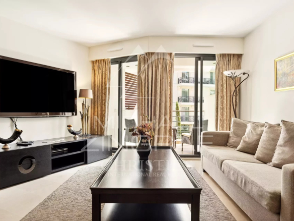 Salon lumineux d'un appartement contemporain à Cannes, avec un canapé et une télévision.