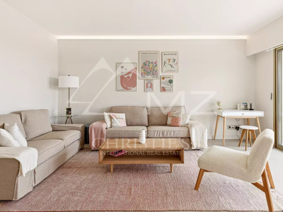 Salon lumineux d'un appartement à Cannes avec un canapé et une table basse.