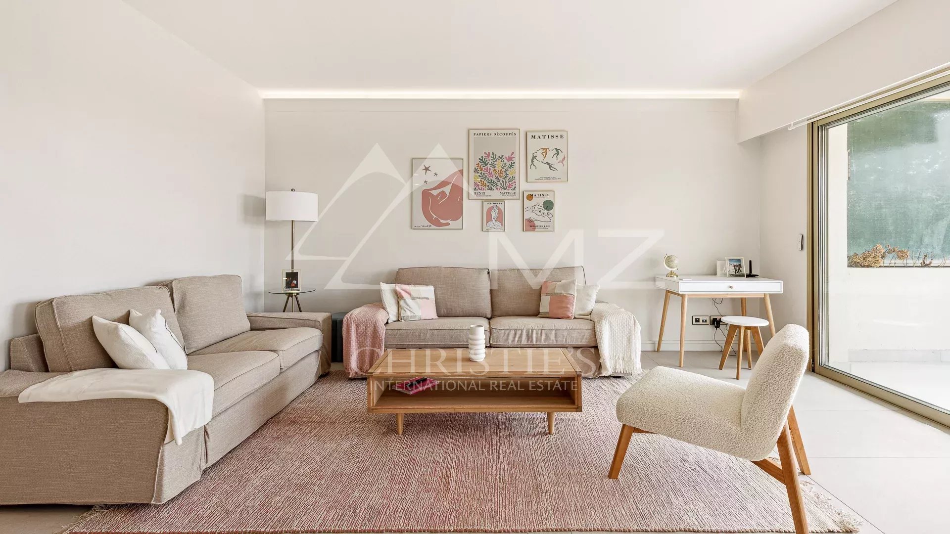 Salon lumineux d'un appartement à Cannes avec un canapé et une table basse.