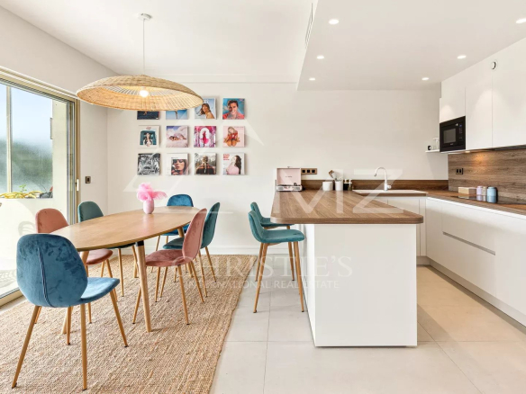 Intérieur d'un appartement à Cannes avec cuisine moderne et salle à manger, grande fenêtre donnant sur la terrasse.