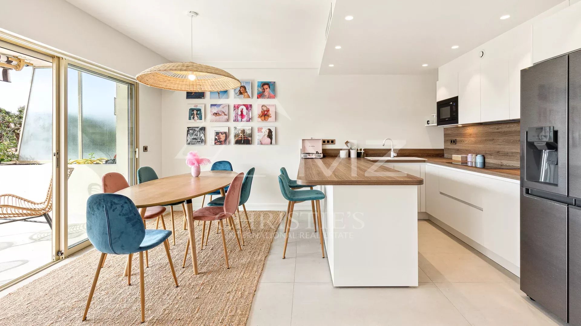 Intérieur d'un appartement à Cannes avec cuisine moderne et salle à manger, grande fenêtre donnant sur la terrasse.
