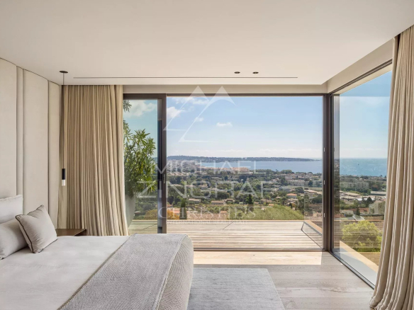 Chambre moderne avec vue sur la mer à Cannes, grandes fenêtres et décoration épurée.