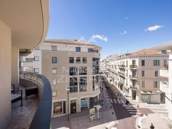 Vue depuis un appartement à Cannes, montrant une rue animée et des bâtiments environnants.