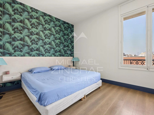 Chambre d'un appartement T4 à Cannes avec un mur décoré de motifs de feuillage.