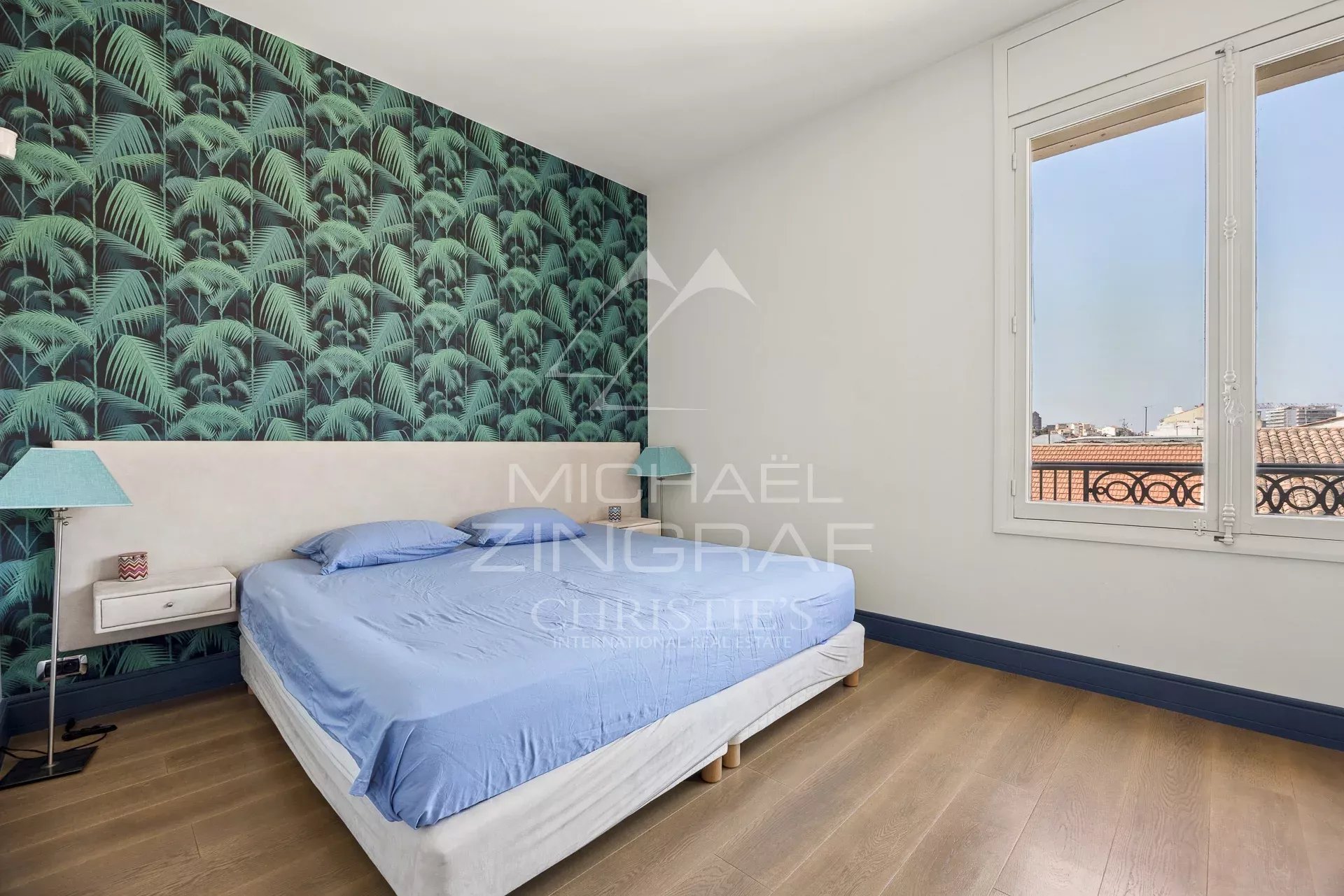 Chambre lumineuse dans un appartement T4 à Cannes Chambre d'un appartement T4 à Cannes avec un mur décoré de motifs de feuillage.