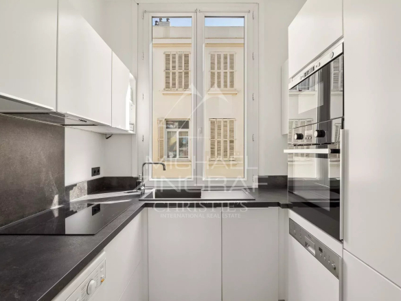 Cuisine moderne et lumineuse d'un appartement T4 à Cannes, avec fenêtres donnant sur l'extérieur.