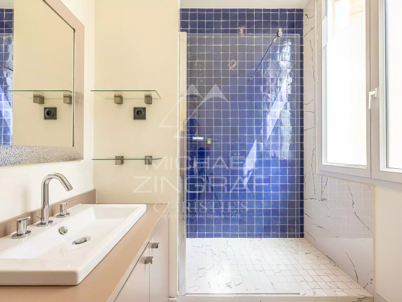 Salle de douche moderne avec carrelage bleu et lavabo dans un appartement au cœur de Cannes.
