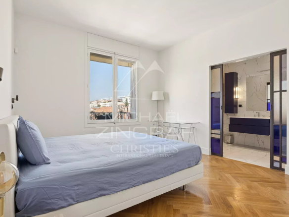 Chambre d'un appartement T4 lumineux à Cannes, avec lit et salle de bain visible en arrière-plan.