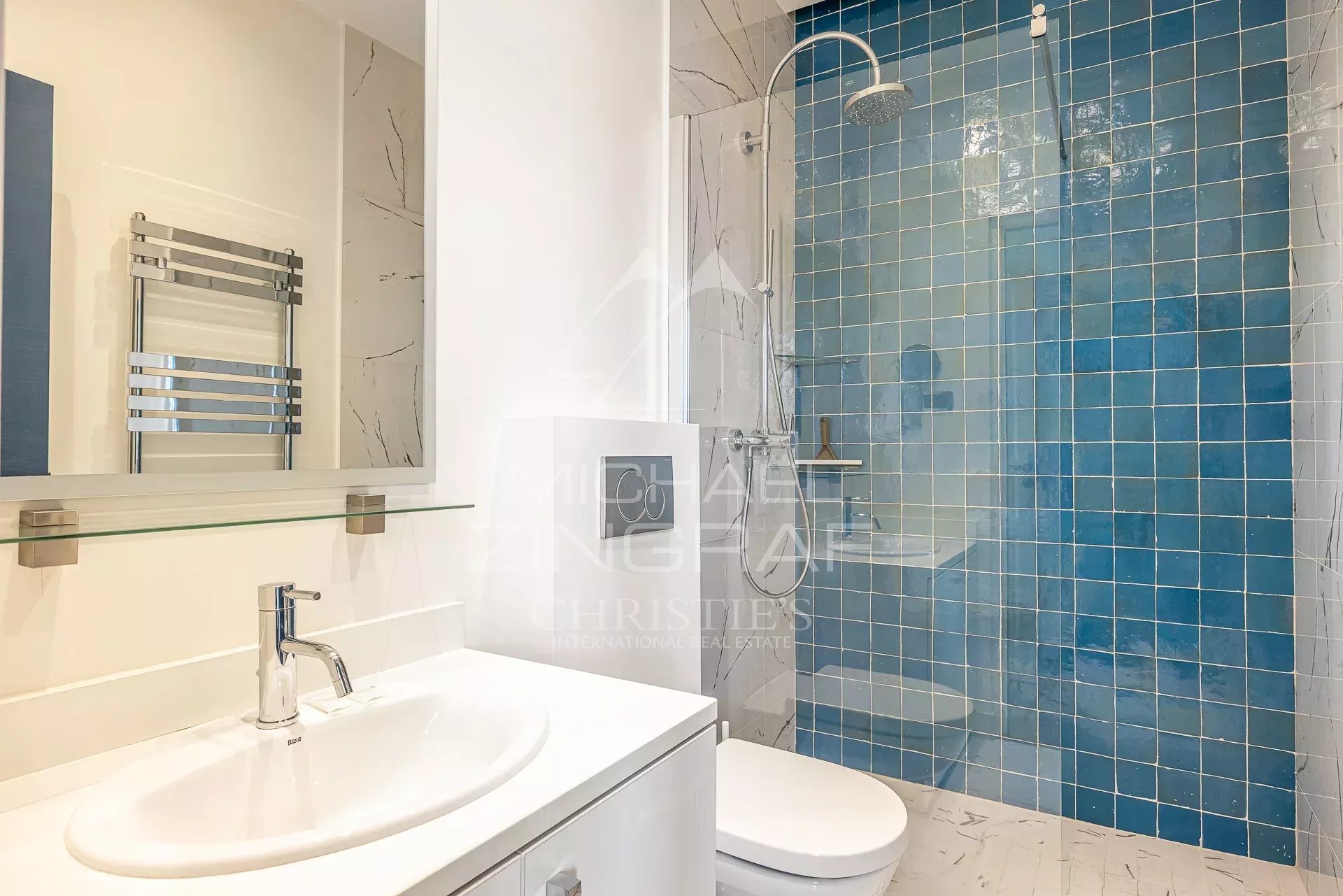 Salle de douche dans un appartement à Cannes Salle de douche moderne avec carrelage bleu et lavabo dans un appartement à Cannes.