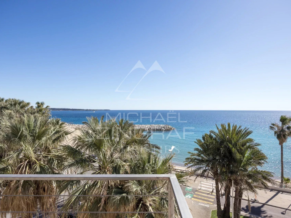 Panoramic sea view from a penthouse in Cannes with palm trees in the foreground.