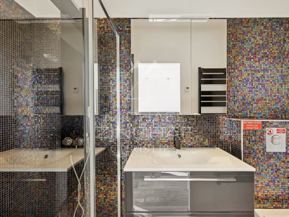 Salle de bain moderne avec carrelage coloré et douche en verre.