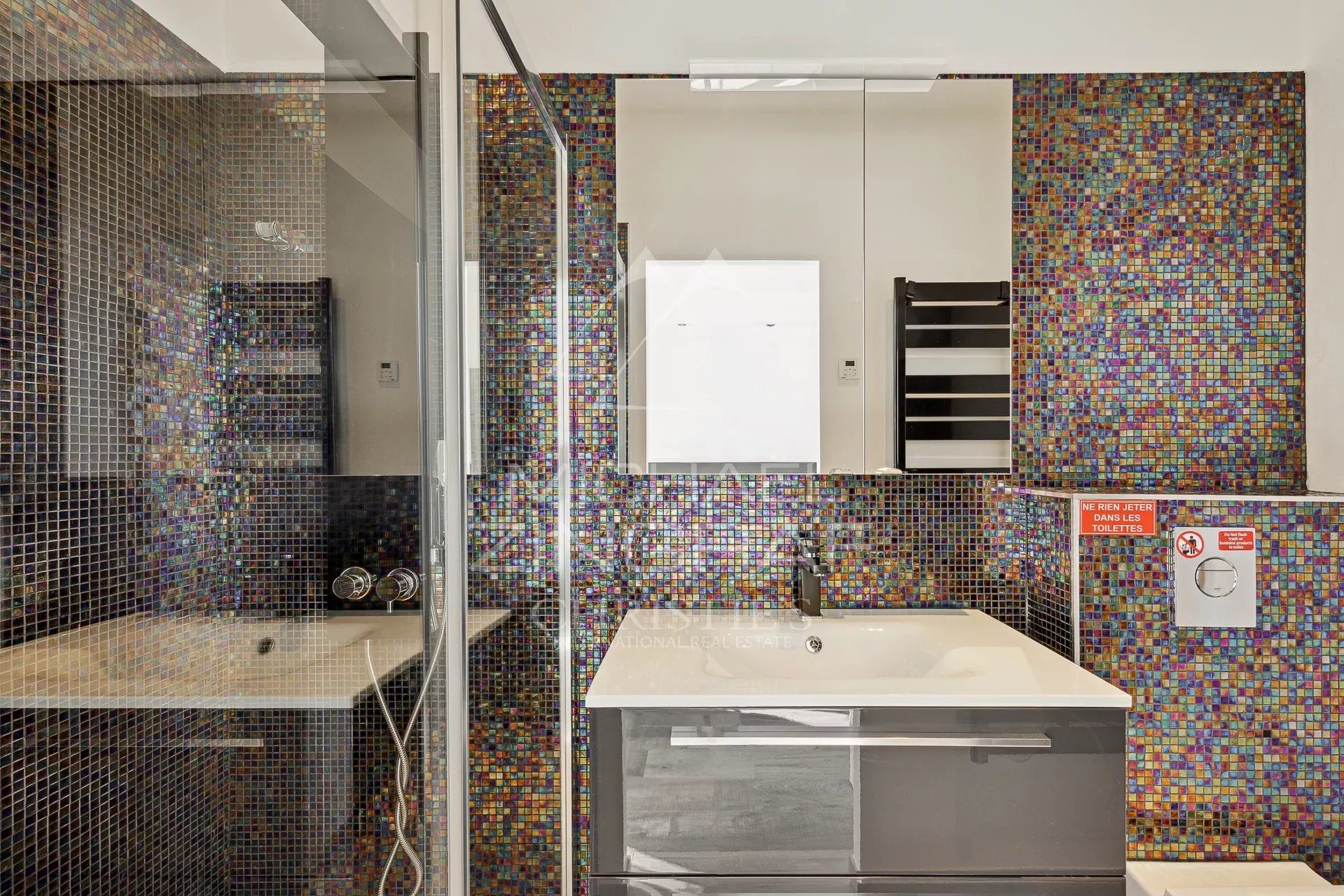 Salle de bain rénovée Salle de bain moderne avec carrelage coloré et douche en verre.