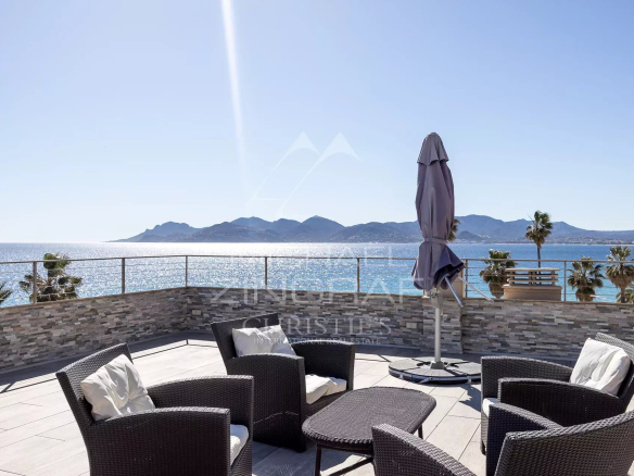 Terrasse sur le toit d'un penthouse à Cannes avec vue sur la mer et des fauteuils en rotin.