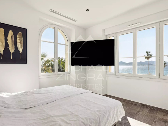 Chambre d'un penthouse avec vue sur la mer à Cannes, fenêtres ouvertes sur la mer et palmiers visibles.