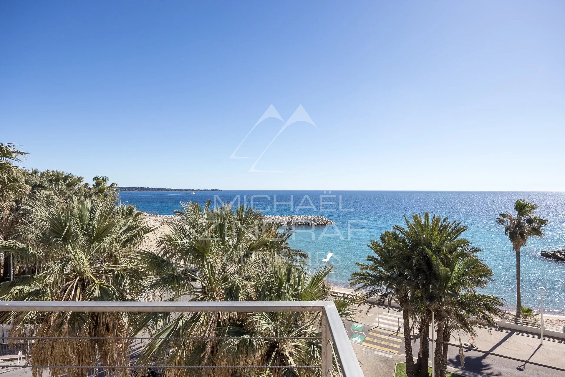 Vue mer depuis un penthouse à Cannes Vue panoramique sur la mer depuis un penthouse à Cannes, entouré de palmiers.