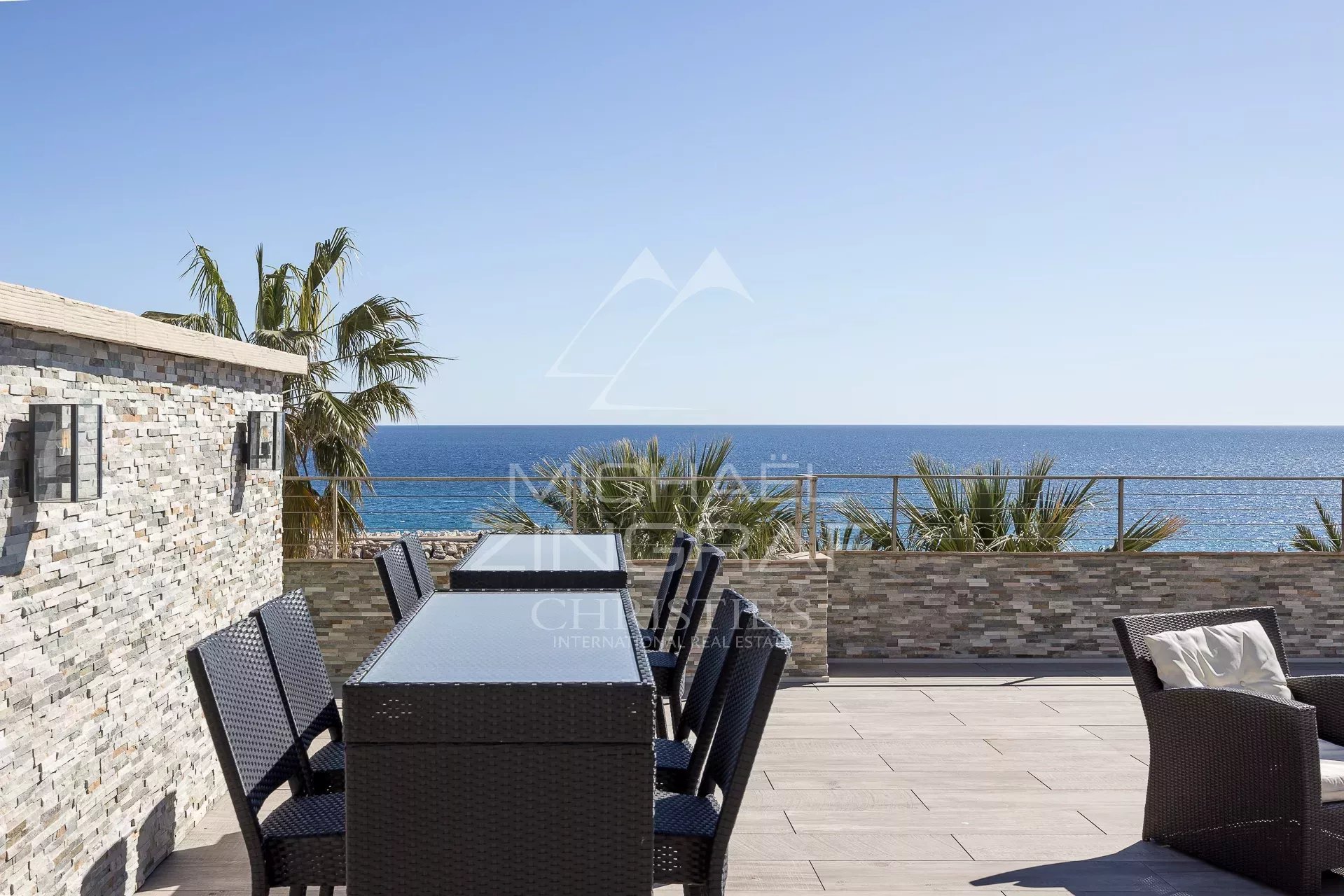 Penthouse avec vue mer à Cannes Terrasse aménagée avec vue sur la mer à Cannes, entourée de palmiers.