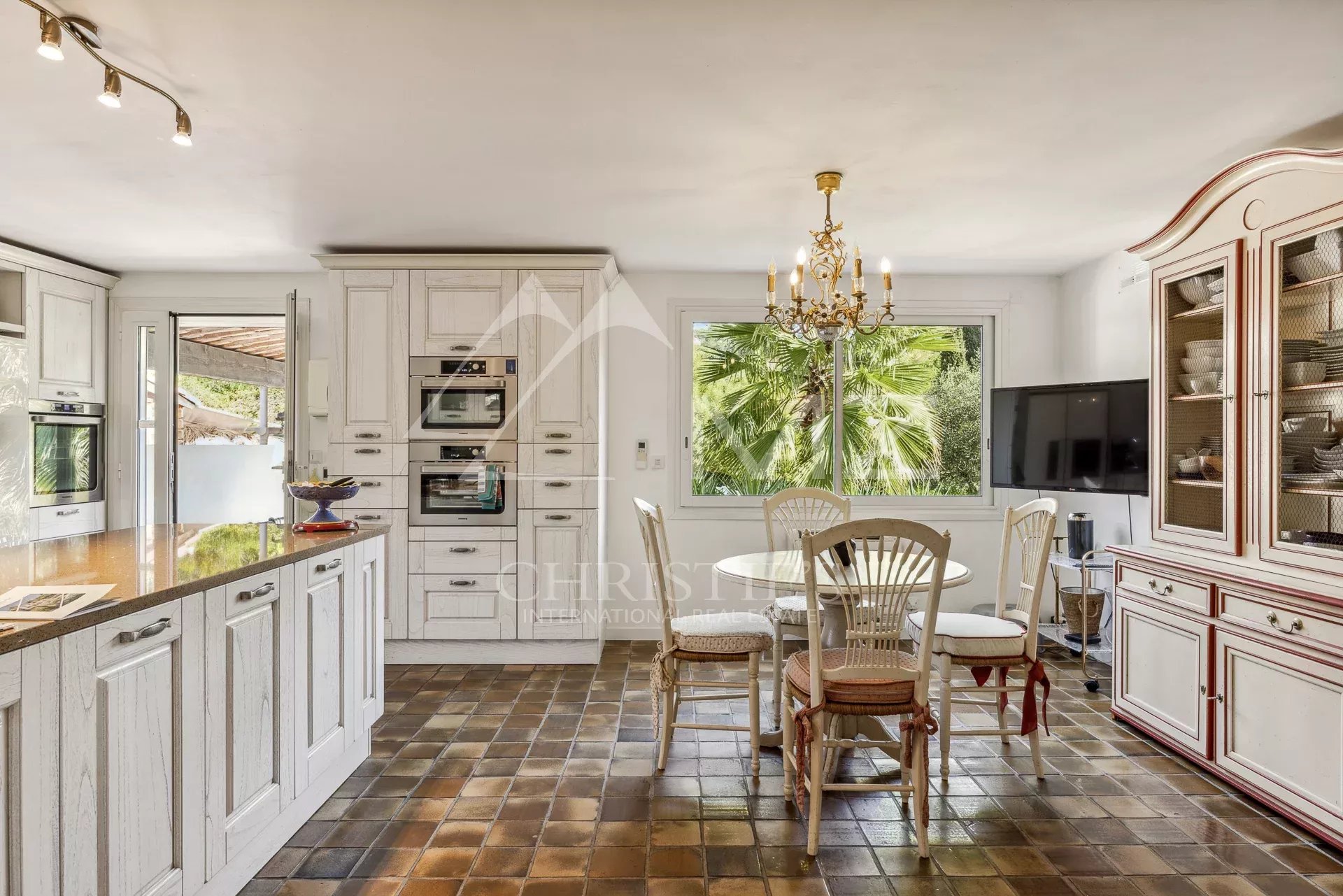 Cuisine d'une villa familiale à Cannes, avec meubles en bois et table à manger.