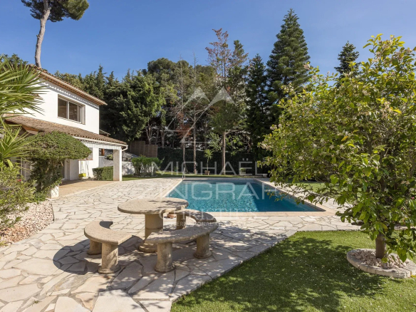 Villa with swimming pool in a gated community in Antibes, surrounded by greenery and a stone outdoor area.