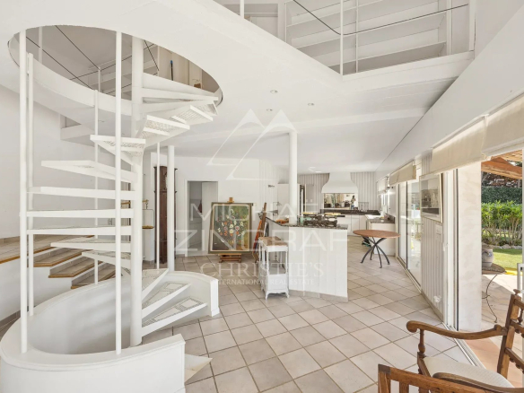 Interior of a villa in Antibes with a spiral staircase and a bright living room.