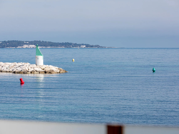 View of the port with a lighthouse and colorful buoys in Cannes, near Palm Beach.