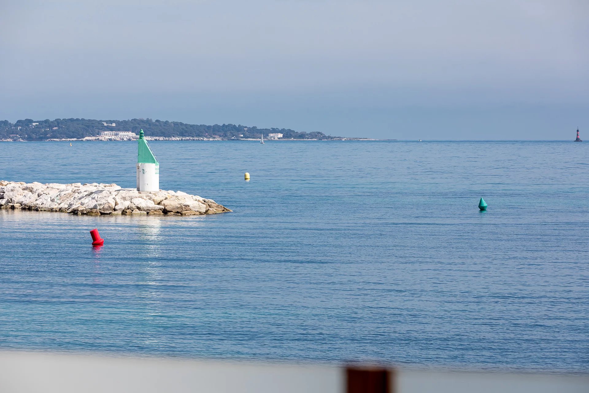 View of the port of Cannes – Palm Beach View of the port with a lighthouse and colorful buoys in Cannes, near Palm Beach.