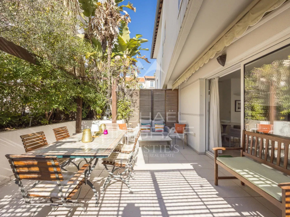 Terrasse d'une villa triplex à Cannes avec mobilier en bois et verdure environnante.