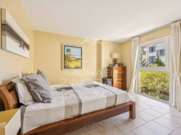 Chambre d'une villa triplex à Cannes, avec fenêtre donnant sur l'extérieur et mobilier en bois.