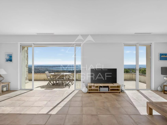 Interior of a stone villa with sea views, bright living room and access to a terrace.