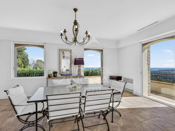 Interior of a stone villa with sea view, dining table and open windows.