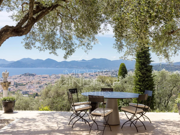 Terrasse avec vue sur la baie de Cannes et l'Estérel, entourée de jardins paysagers.