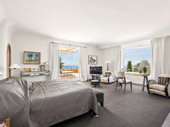 Chambre spacieuse avec vue sur la baie de Cannes, décorée avec des meubles élégants.