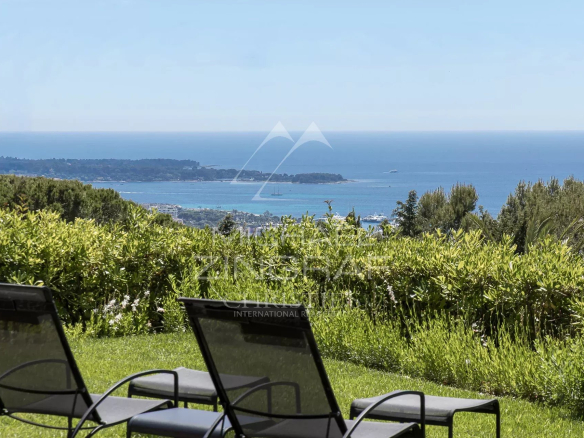 Vue sur la baie de Cannes depuis un jardin paysager avec des chaises longues.