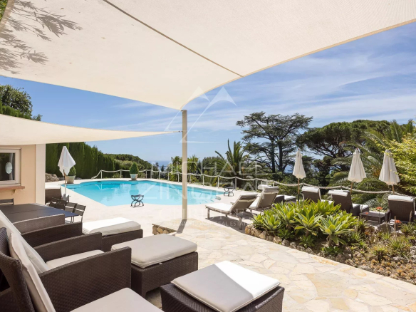 Terrasse avec piscine et vue sur la baie de Cannes, entourée de jardins paysagers.