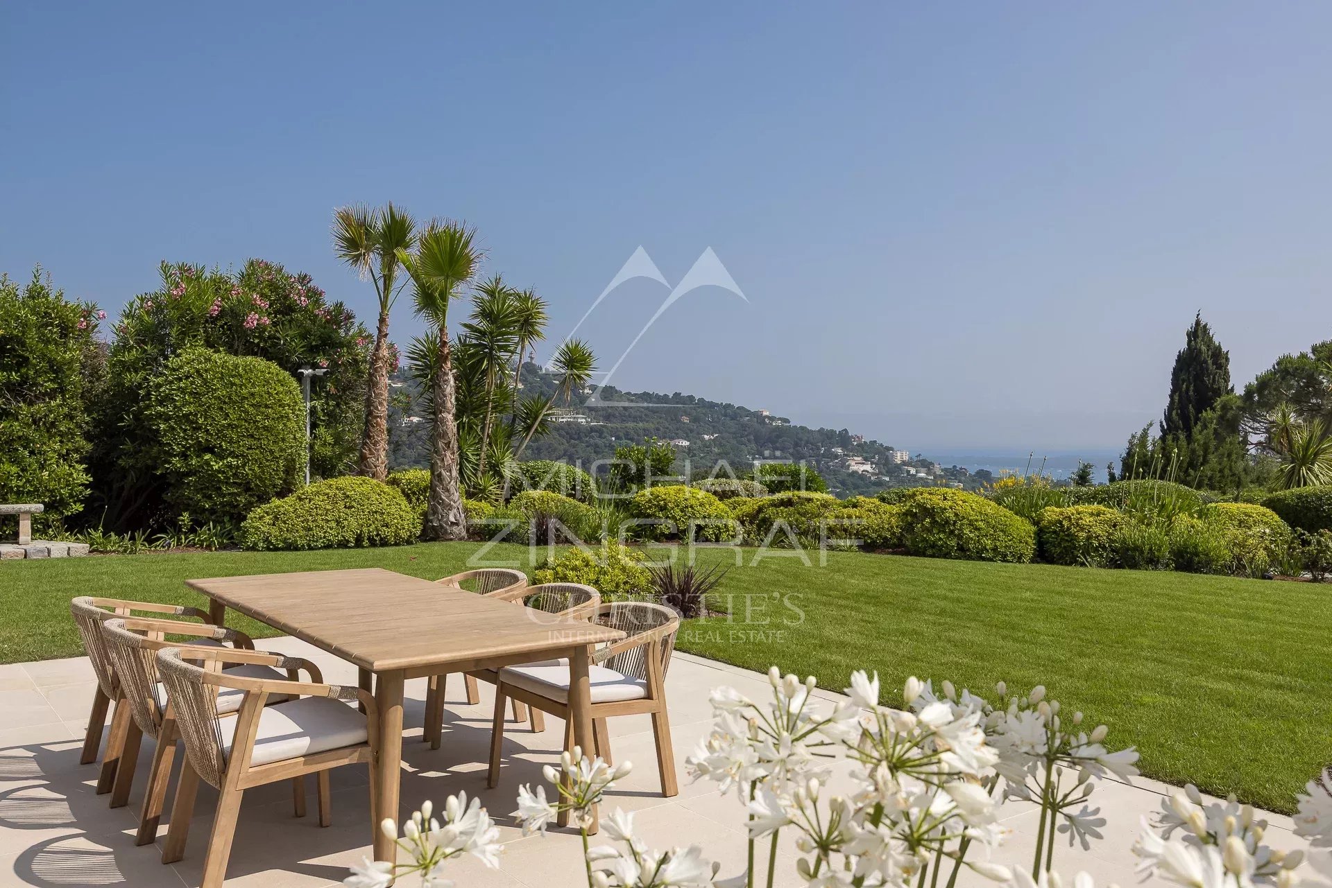 Propriété avec vue mer à Cannes-Californie Terrasse ensoleillée avec mobilier en bois et vue sur la mer à Cannes-Californie.
