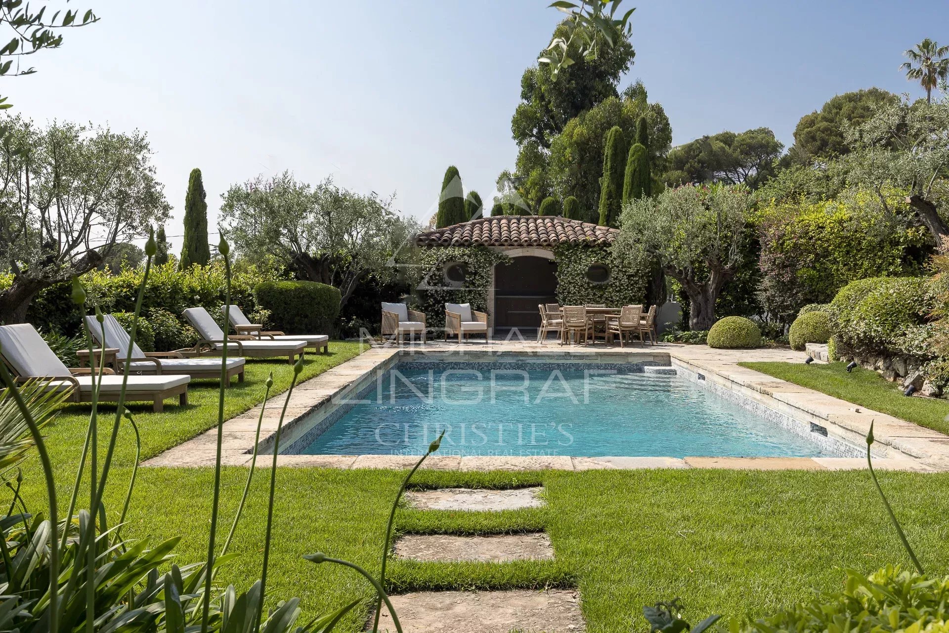 Villa avec piscine à Cannes-Californie Piscine entourée de chaises longues et jardin paysager dans une villa à Cannes-Californie.