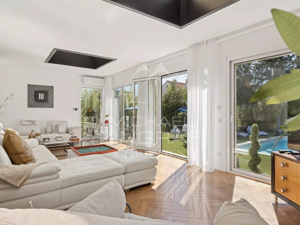 Intérieur d'une villa Art Déco rénovée avec un salon lumineux et des fenêtres donnant sur le jardin.