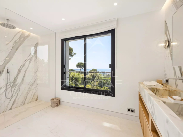 Modern bathroom with sea view in Cannes, marble walls and open window.