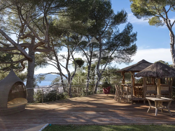 Wooden terrace with furniture, sea view and surrounding trees in Cannes.