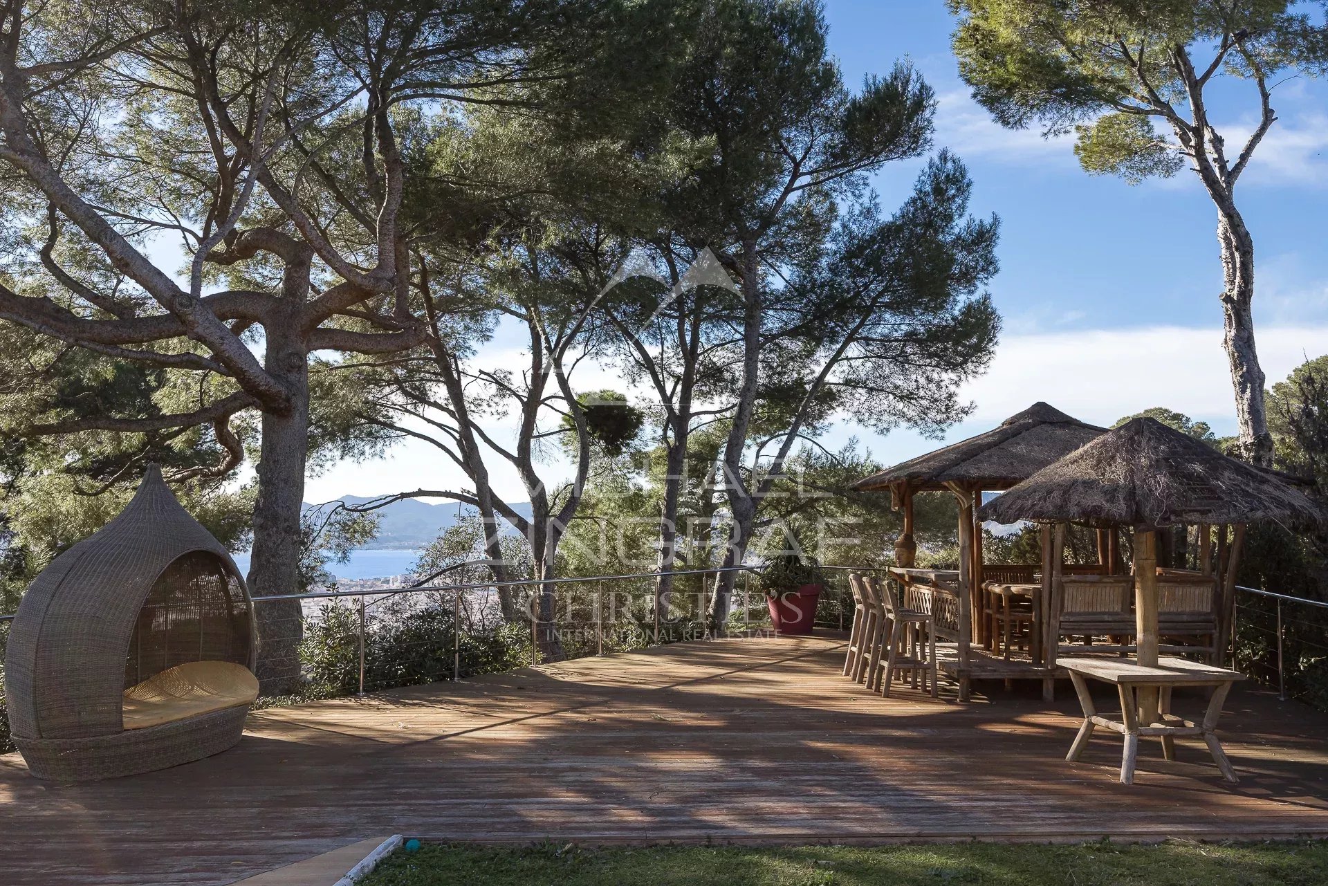 Panoramic terrace in Cannes Wooden terrace with furniture, sea view and surrounding trees in Cannes.